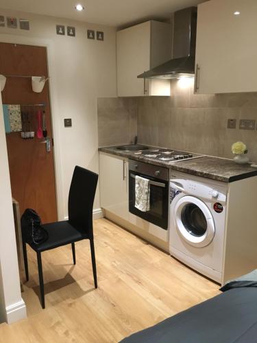 a kitchen with a washing machine and a chair at Studio flat in the heart of Golders Green in London