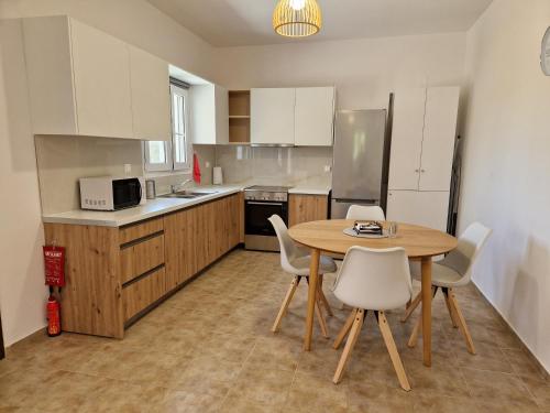 a kitchen with a wooden table and white chairs at MemRo Village House in Atsoupádhes