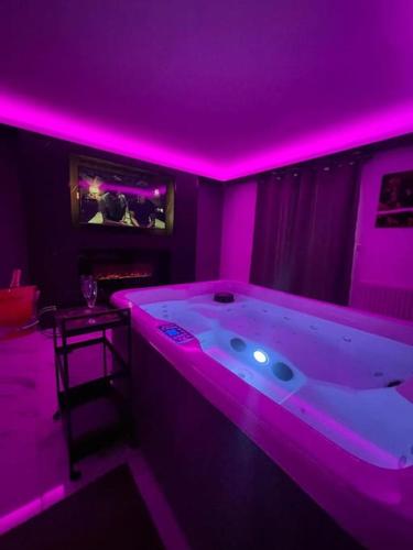 a room with a large tub with purple lighting at La Suite Casa Dé lové 2.0 jacuzzi & cinema privé in Melun