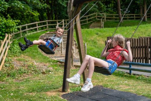 Un chico y una chica sentados en un columpio en Watermouth Lodges en Ilfracombe