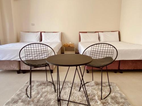 two chairs and a table in a room with a bed at Muchen BnB in Magong