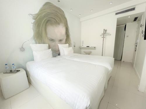 a woman is looking at a large white bed at Blc Design Hotel in Paris