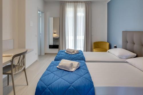 a hotel room with two beds and a desk at Oleandro Holiday Apartments in Bardolino