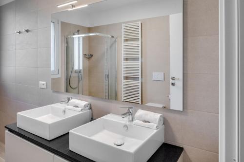 ein Badezimmer mit zwei weißen Waschbecken und einem Spiegel in der Unterkunft Oleandro Holiday Apartments in Bardolino
