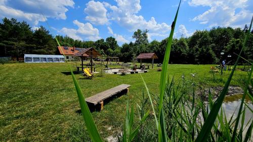 a park with benches and a playground in the grass at Kemping i Domki nad stawem in Harsz