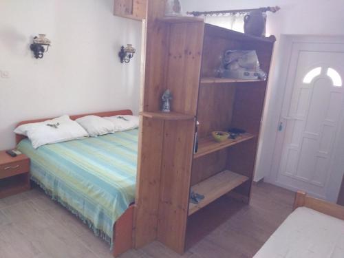 a bedroom with a bed with a wooden book shelf at Apartmani Kasteljan 7, Stara novalja in Stara Novalja
