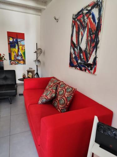 a red couch in a living room with paintings at House Il Conte in Palermo