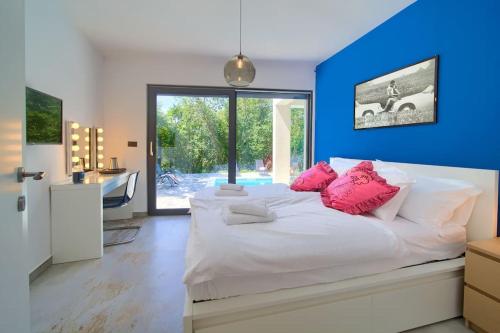 a bedroom with a large white bed with pink pillows at Wellness villa Modruna in Grižane