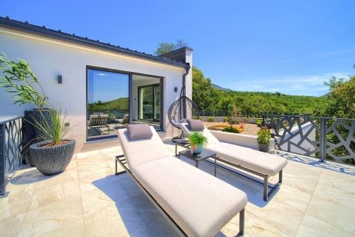 a patio with two couches and chairs on a balcony at Wellness villa Modruna in Grižane