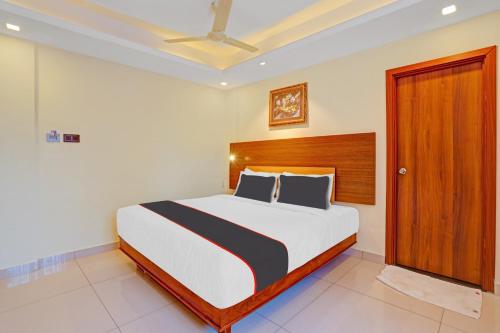 a bedroom with a large bed with a wooden headboard at Hotel Pallava Rajadhani in Trivandrum