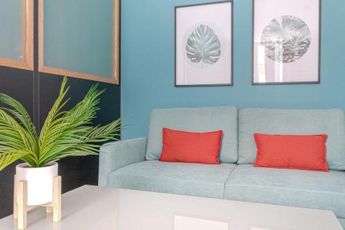 - un salon bleu avec un canapé bleu et des oreillers rouges dans l'établissement Le voyageur de chinchauvaud, à Limoges