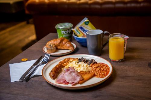 a table with two plates of breakfast food and orange juice at ibis Styles Glasgow Central in Glasgow