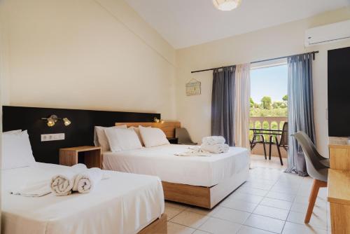 a hotel room with two beds and a balcony at Riposo Studios & Apartments in Kavos