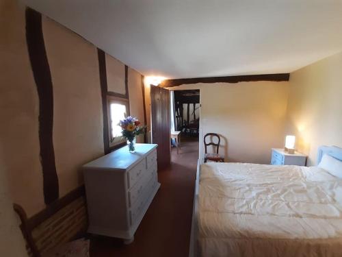 Un dormitorio con una cama y un jarrón de flores en un tocador en Les Hautes Charmante Ferme solognote en Ligny-le-Ribault