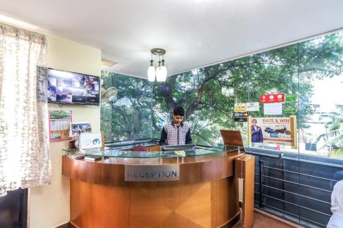 a man sitting at a reception desk with a laptop at OYO Flagship 81536 Royal Classio in Bangalore