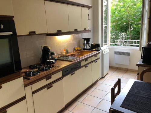 eine Küche mit weißen Schränken, einem Tisch und einem Fenster in der Unterkunft Au pied du Marché in La Châtre