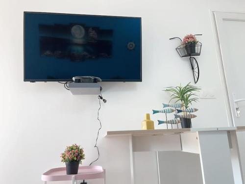 telewizor wiszący na ścianie w pokoju z roślinami w obiekcie Le MonMon des Minimes w La Rochelle