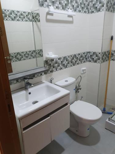 a bathroom with a toilet and a sink and a mirror at Appartement standing in Martil