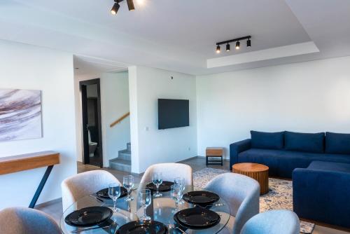 una sala da pranzo con tavolo, sedie e divano blu di Luna Taghazout - Duplex Luxe - 4 Px a Taghazout