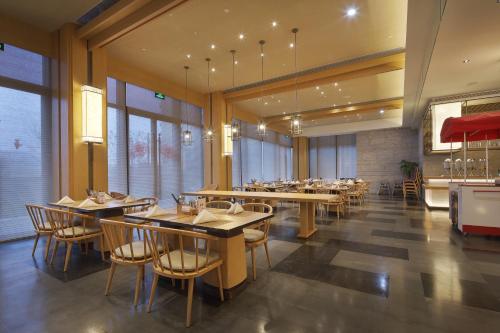 um restaurante com mesas e cadeiras de madeira e janelas em Crowne Plaza Nanchang Wanli, an IHG Hotel em Nanchang
