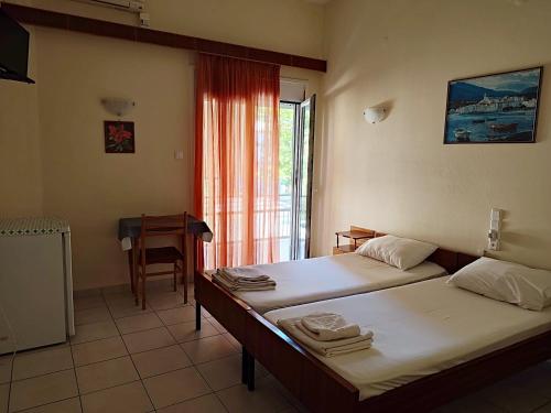 Zimmer mit 2 Betten, einem Tisch und einem Fenster in der Unterkunft ΠΕΡΣΕΦΟΝΗ in Kamena Vourla