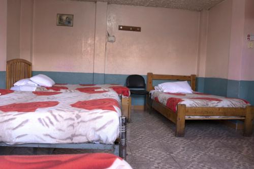 a bedroom with two beds and a chair in it at Hostal Carlos Luis in Quito