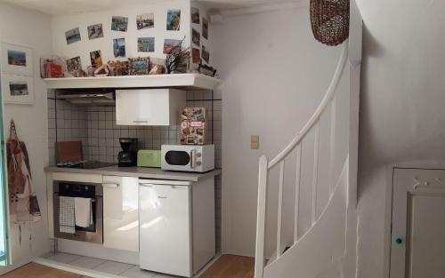 a small kitchen with a microwave and a staircase at Jetez l'ancre dans notre maison de pêcheur ! in Collioure