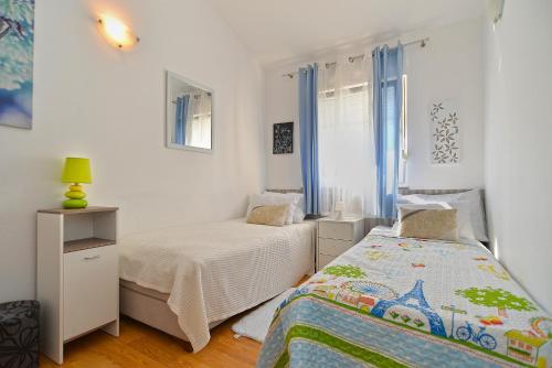 sypialnia z 2 łóżkami i oknem z niebieskimi zasłonami w obiekcie House Kacana 2163 w mieście Vodnjan