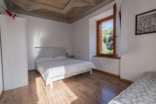 a white bedroom with a bed and a window at Ride Home - Val di Sole in Commezzadura
