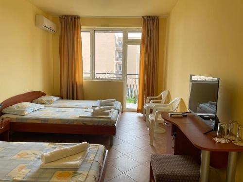 a room with two beds and a desk and a window at Family hotel Summer in Ravda
