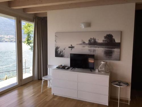 ein Wohnzimmer mit einem TV auf einer weißen Kommode in der Unterkunft The House on the lake shore in Dervio