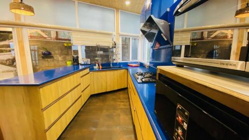 une grande cuisine avec des comptoirs bleus et une cuisinière dans l'établissement Clarence Cottage, à Mussoorie