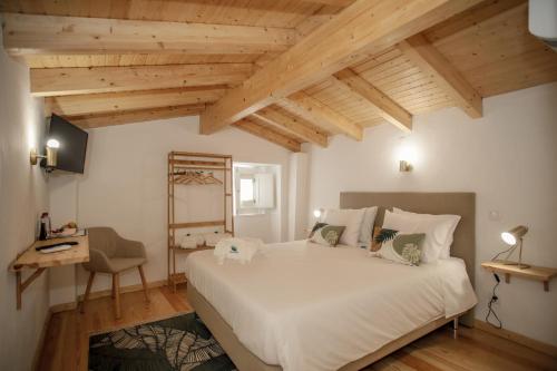 - une chambre avec un grand lit blanc et des plafonds en bois dans l'établissement Óbidos Pátio House, à Óbidos