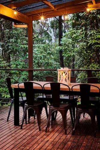 a wooden table and chairs on a wooden deck at Romantic Getaway - 2 luxe outdoor baths in Mount Macedon