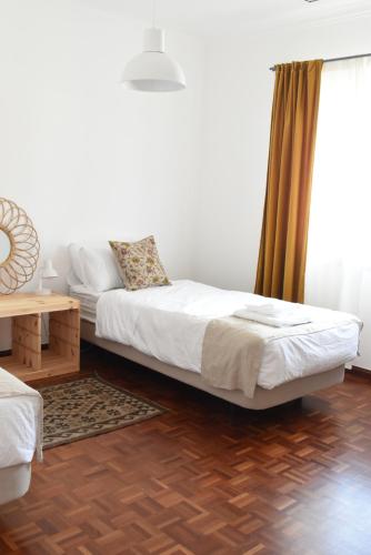 um quarto com uma cama, uma mesa e uma janela em Ericeira Living em Ericeira