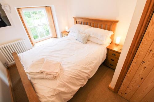 a bedroom with a large white bed with a window at Sedbergh Cottage, Sedbergh in Sedbergh