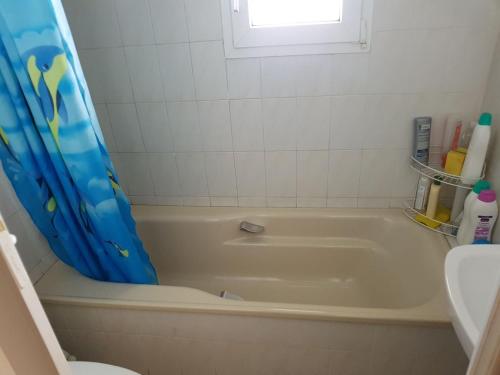 a bathroom with a bath tub with a blue shower curtain at urb el refugio , brañavieja-alto campoo in Brañavieja