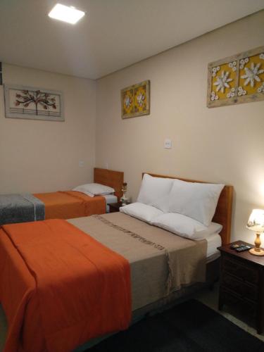 a hotel room with two beds with orange sheets at Casa Temporada Tiradentes in Tiradentes