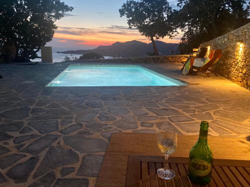 a bottle of wine sitting on a table next to a pool at VILLA NOVA Leros in Drymonas