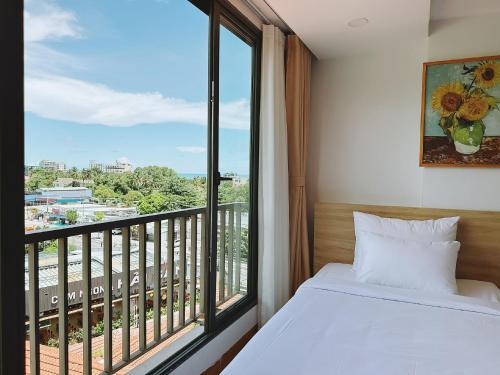a bedroom with a bed and a large window at Rosie Balcony Hotel Phu Quoc in Phu Quoc