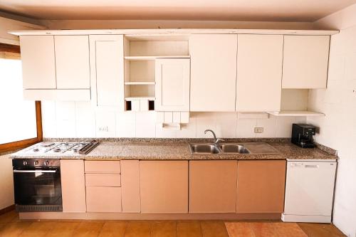 a kitchen with white cabinets and a sink at Pulli's Home - Comfy&Cozy House in Selargius