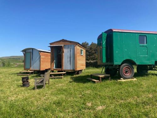 a green truck parked in a field with two tiny homes at Renison's Farm in Penrith