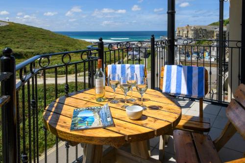 een houten tafel met wijnglazen op een balkon bij Beachcombers Apartments in Newquay