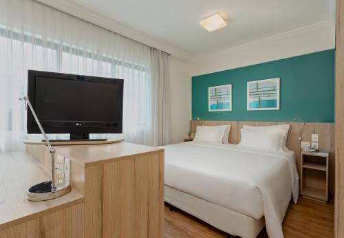 um quarto com uma cama e uma televisão de ecrã plano em Radisson Oscar Freire em São Paulo