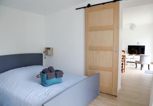 ein Schlafzimmer mit einem Bett mit einer blauen Tasche darauf in der Unterkunft Gîte Les amoureux de la Baie in Favières