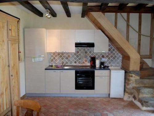 une cuisine avec des armoires blanches et un appareil noir dans l'établissement Gîte charmant avec piscine chauffée, tennis et jardin près de Beaumont-sur-Sarthe - FR-1-410-214, à Maresché