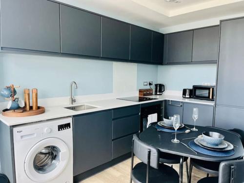 a kitchen with a washing machine and a table with chairs at Beautifully presented one bedroom apt close to Old Trafford Stadium in Manchester