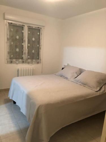- un lit blanc dans une chambre avec fenêtre dans l'établissement VILLA MARYSABEL , maison T4 duplex, résidence villa de melody avec 2 piscines, mer à 500 m, à Santa-Maria-Poggio