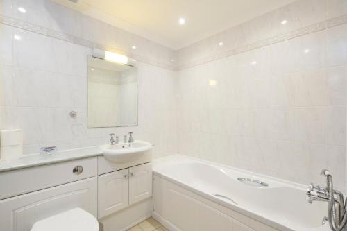 a white bathroom with a sink and a tub and a toilet at Beachcombers Apartments in Newquay