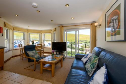 a living room with a blue leather couch and a table at Beachcombers Apartments in Newquay